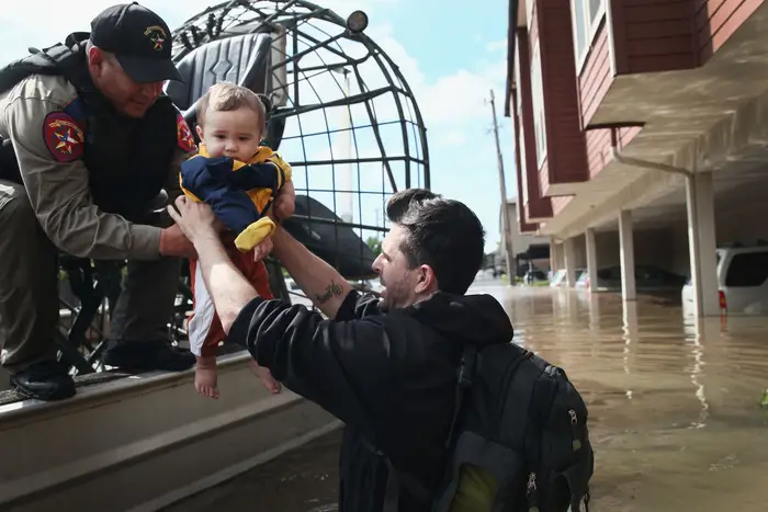 Michael Boyd passes his son Skylar over to a rescue worker as they are evacuated on an airboat from their apartment complex after it was inundated with water following Hurricane Harvey on August 30, 2017 in Houston, Texas. It was Skylar's first birthday<br>(Getty Images)